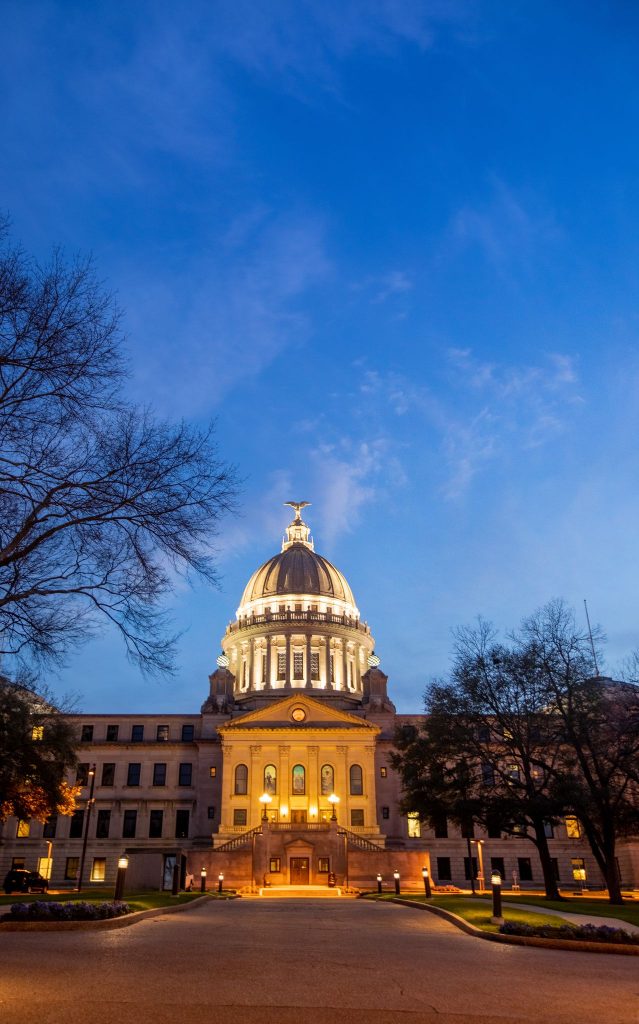 A ground view of the Jackson capital building lit up at night in Mississippi